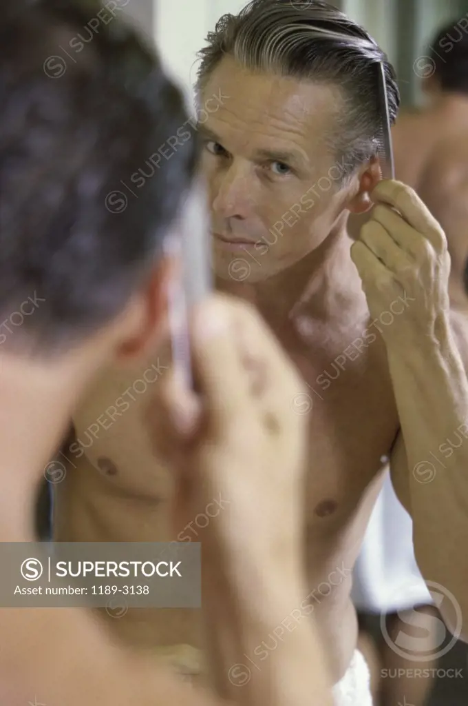 Mid adult man combing his hair