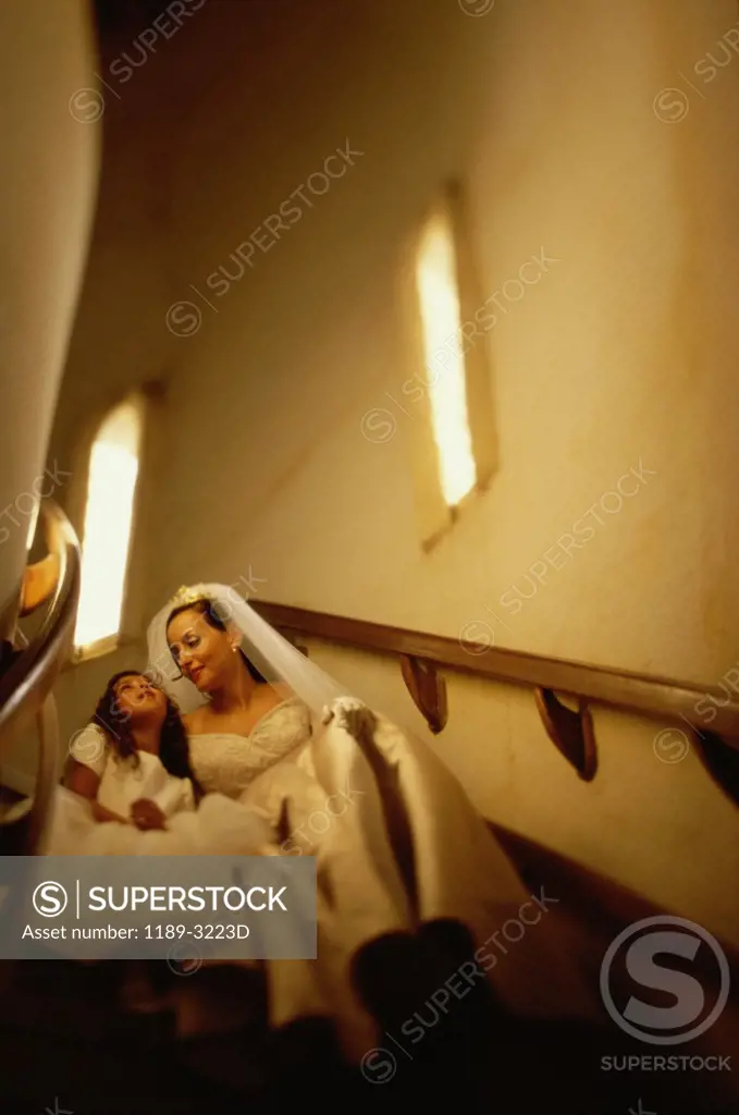 Low angle view of a bride sitting with a flower girl on a staircase