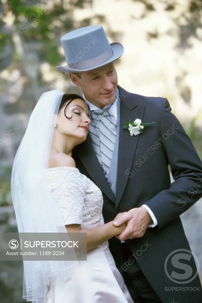 Close-up of a newlywed couple standing holding hands