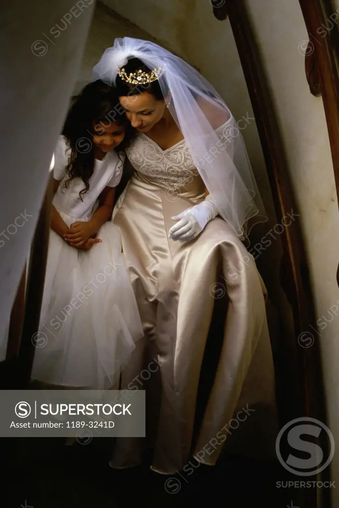 Bride sitting with a flower girl on a staircase
