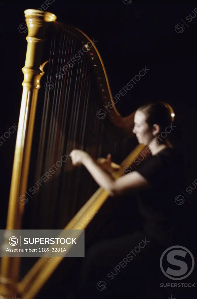 Side profile of a young woman playing the harp
