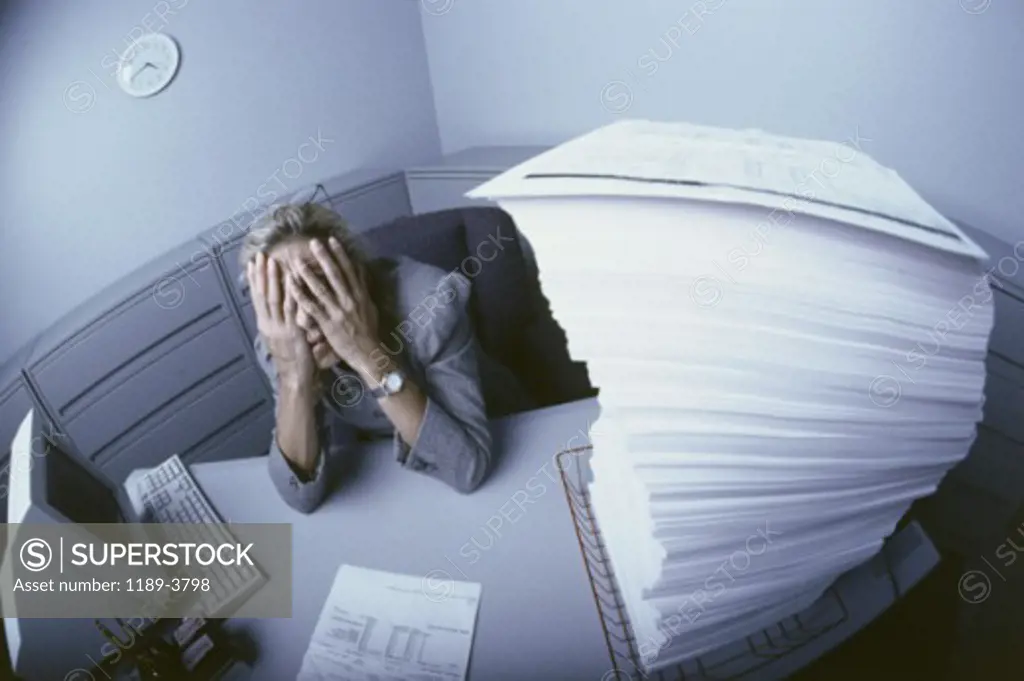 Businesswoman sitting at a desk with her hands covering her face