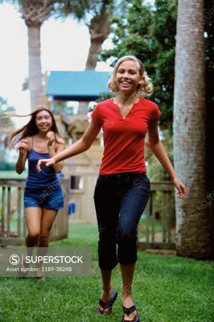 Two teenage girls running in a park