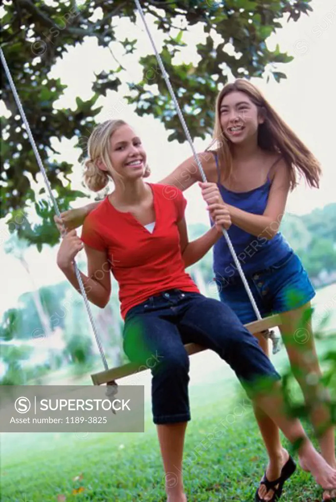 Two teenage girls swinging on a swing