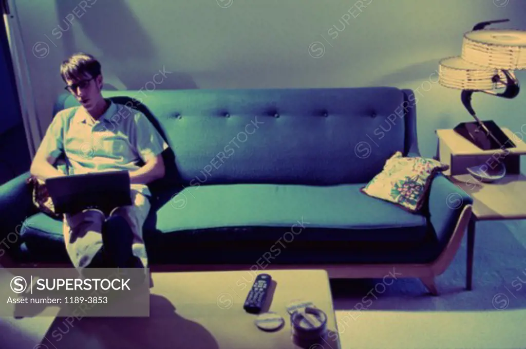 Young man sitting on a couch using a laptop