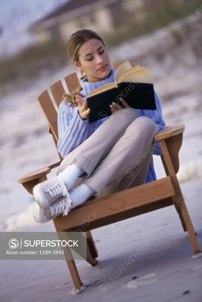 Young woman reading a book on the beach