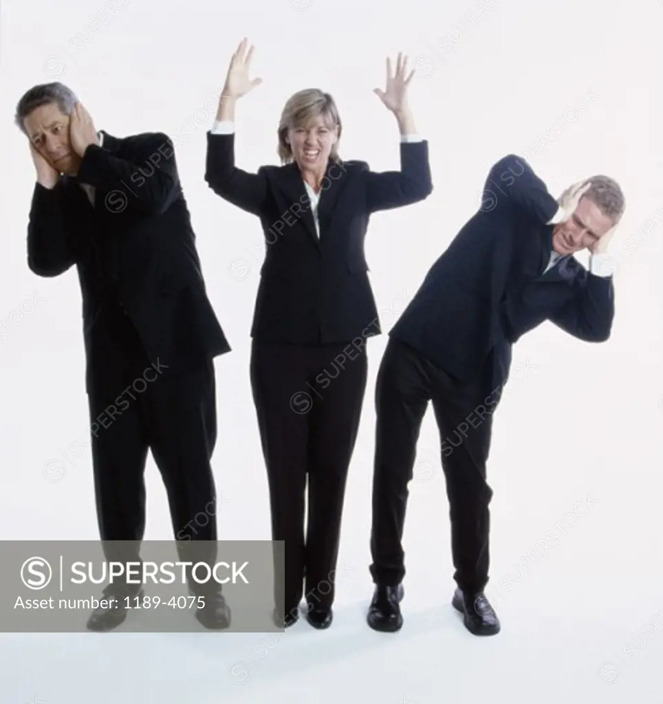 Two businessmen covering their ears with a businesswoman shouting