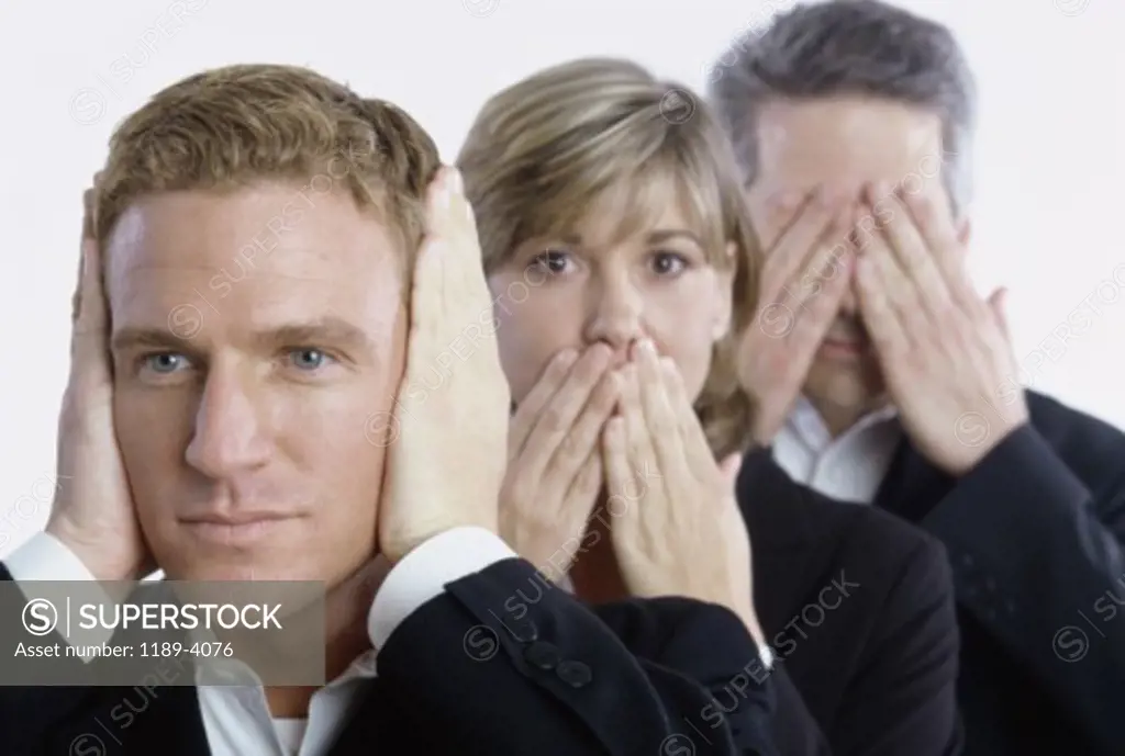 Two businessmen and a businesswoman covering their mouth ears and eyes