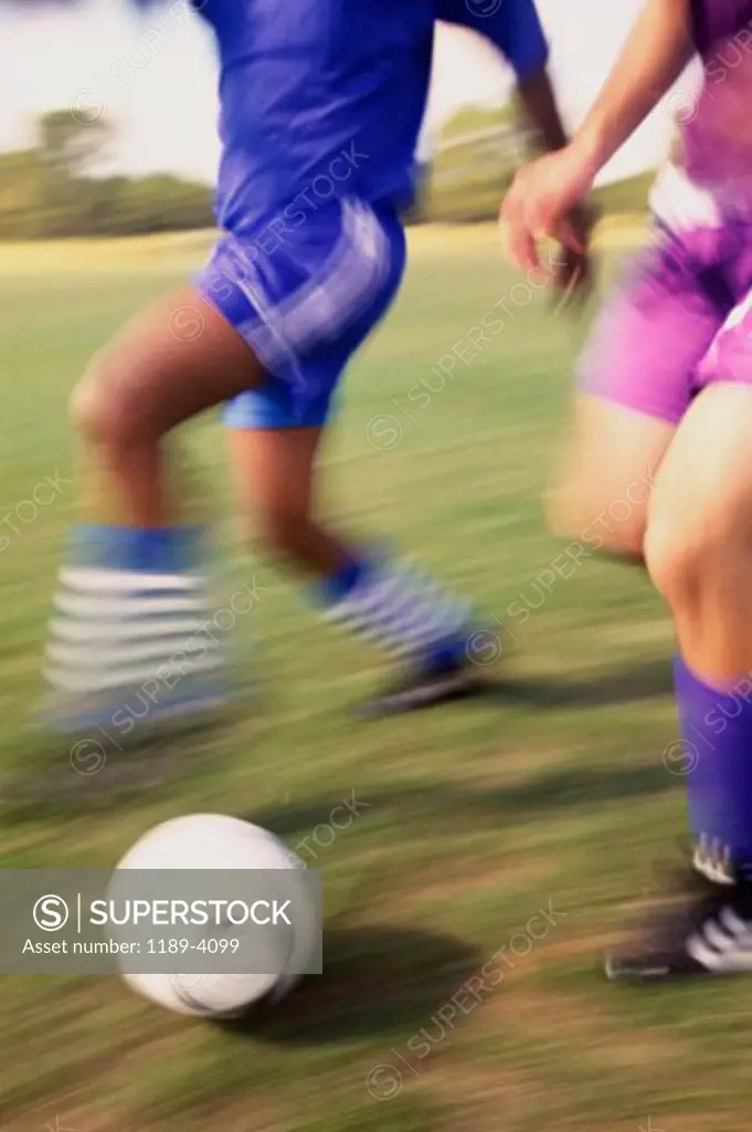Low section view of two soccer players playing with a soccer ball
