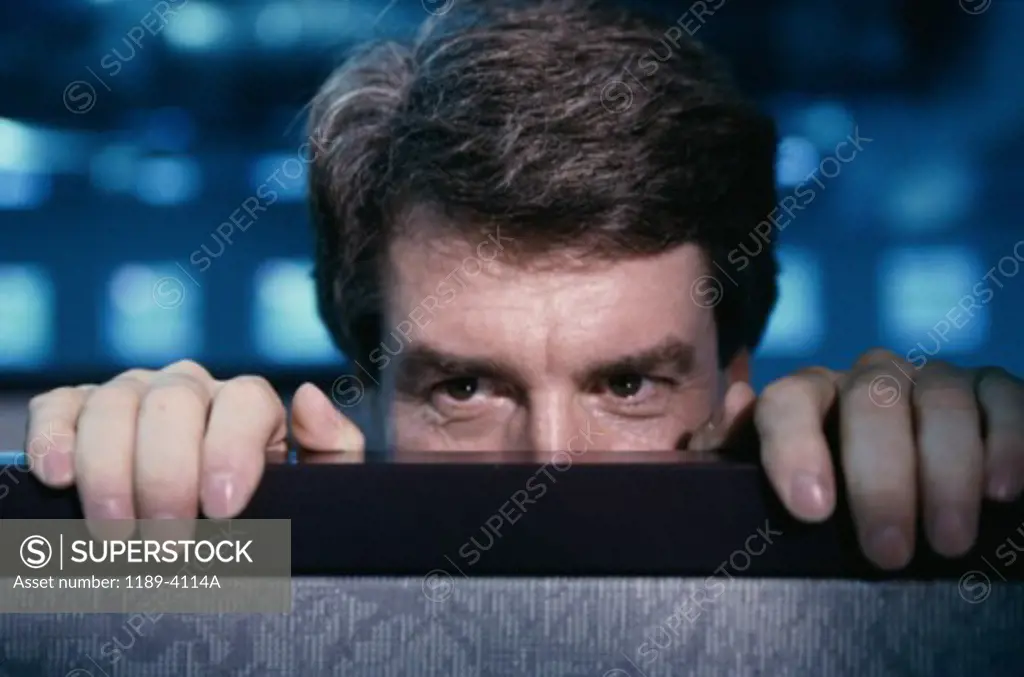 Businessman hiding behind an office cubicle