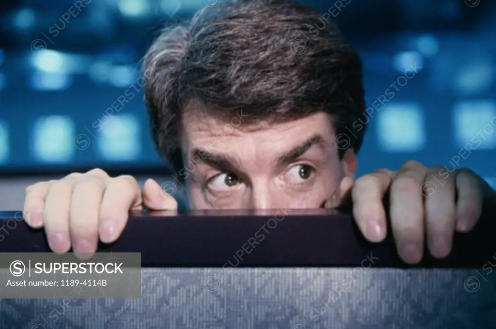 Businessman hiding behind an office cubicle