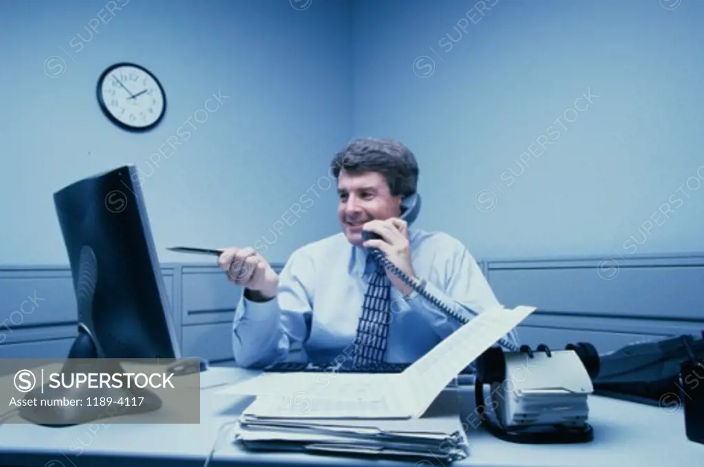 Businessman working on a computer and talking on the telephone