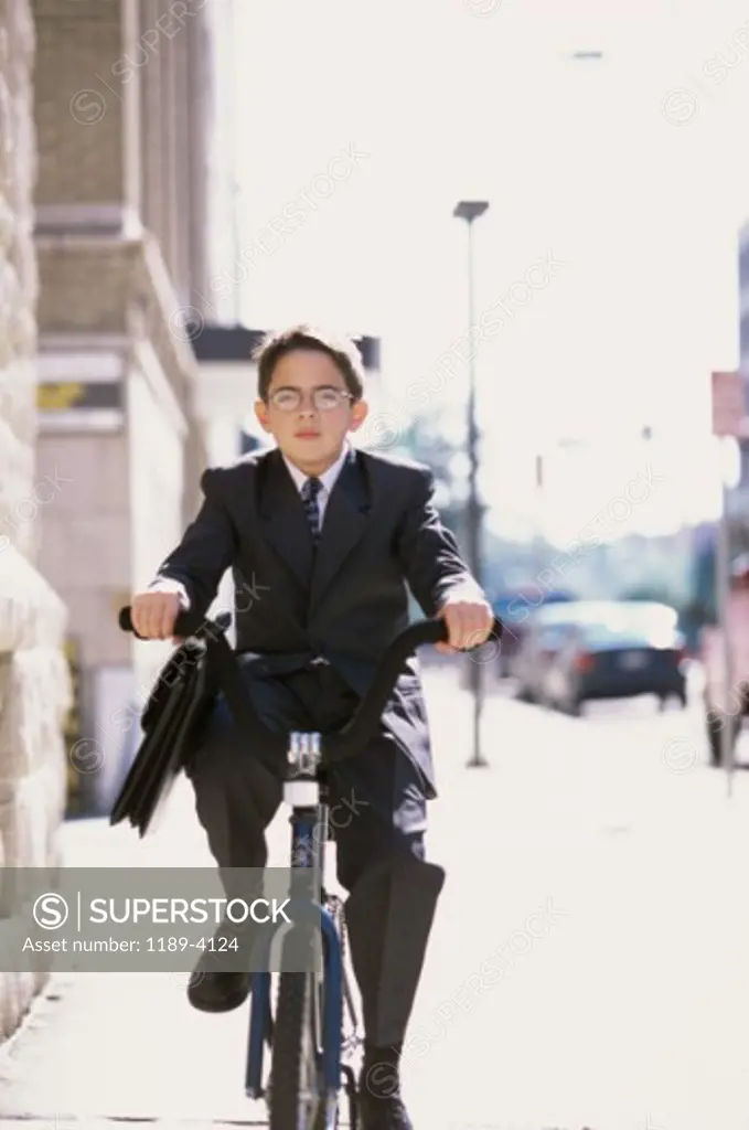 Portrait of a boy riding a bicycle wearing a business suit