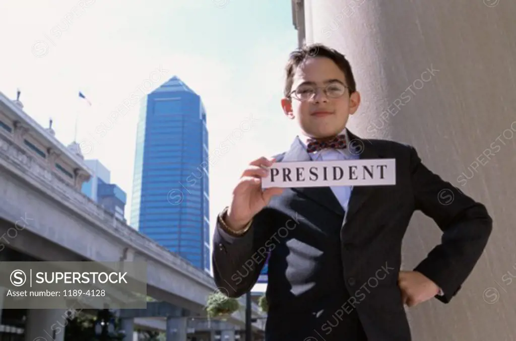 Portrait of a boy holding a placard with the word president