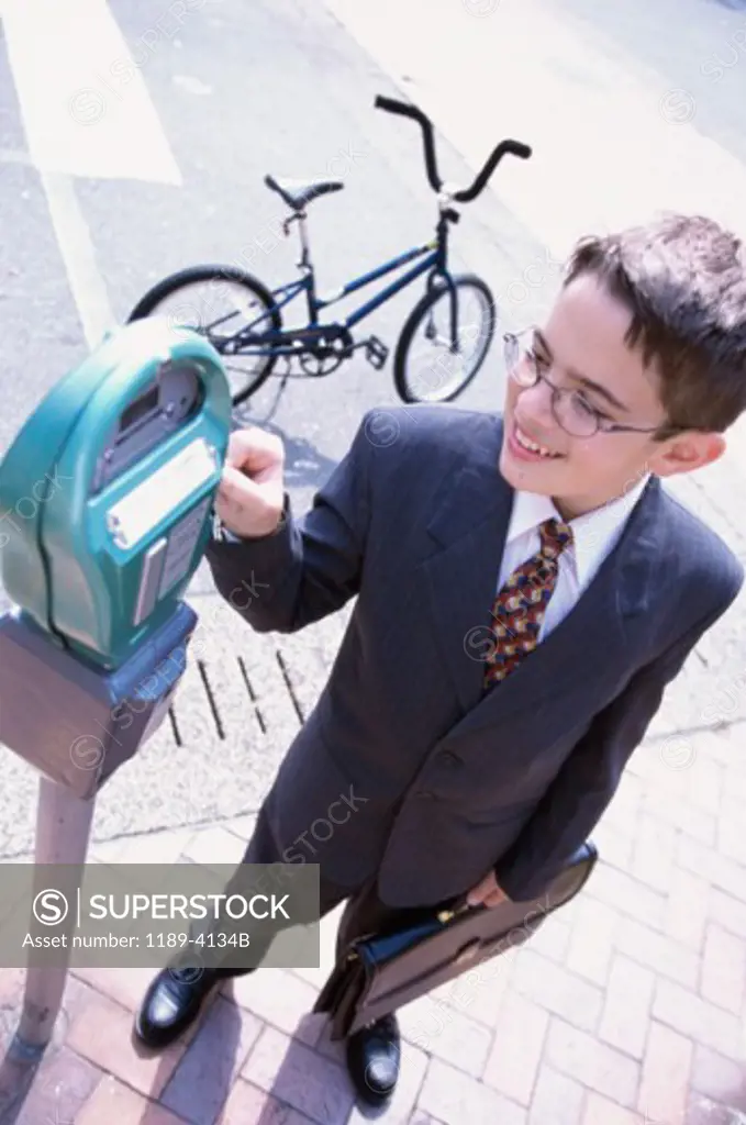 High angle view of a boy wearing a business suit operating a parking meter