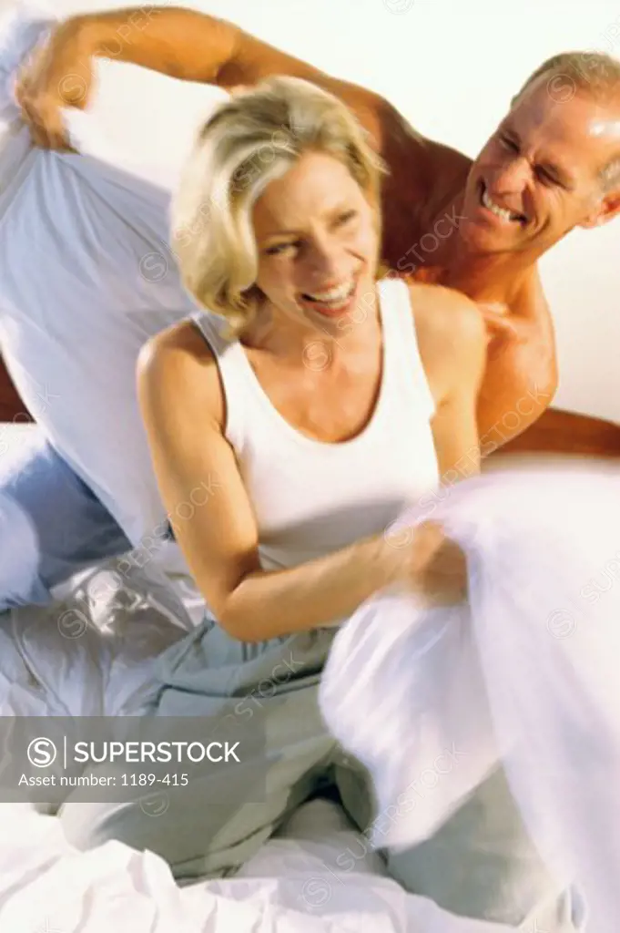 Close-up of a mid adult couple having a pillow fight
