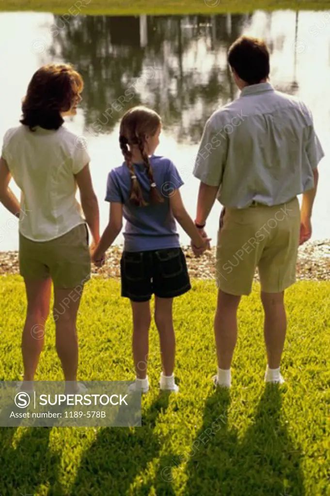 Rear view of a mid adult couple with their daughter standing in front of a lake