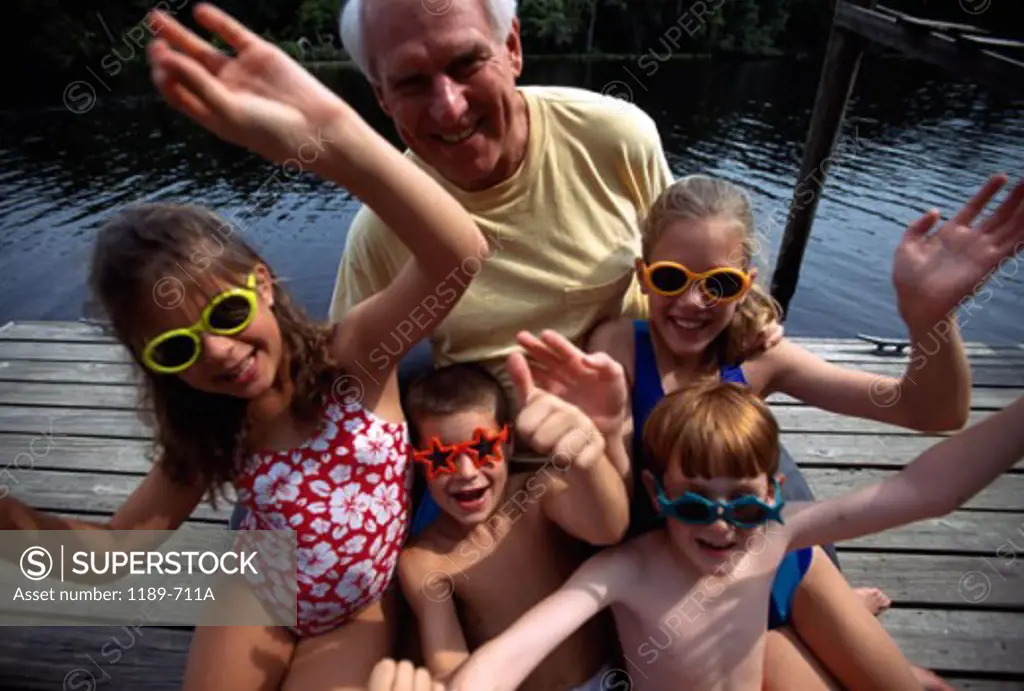High angle view of a senior man sitting with his grandchildren on a pier