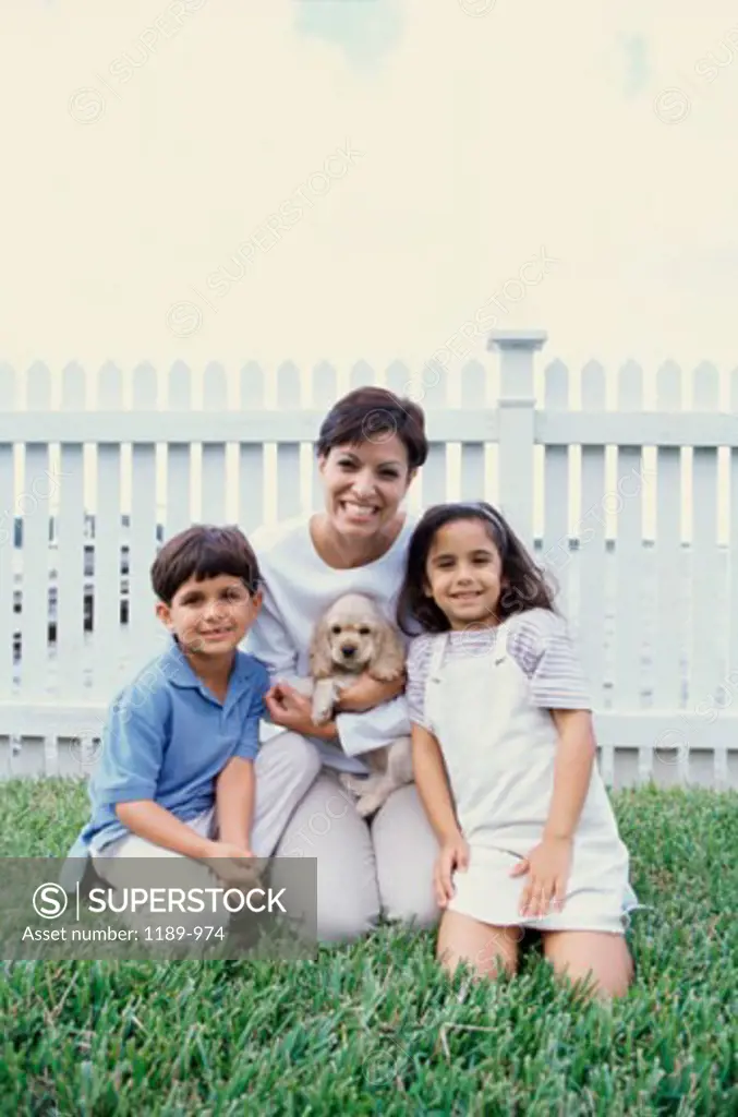 Portrait of a mother holding a puppy smiling with her two children