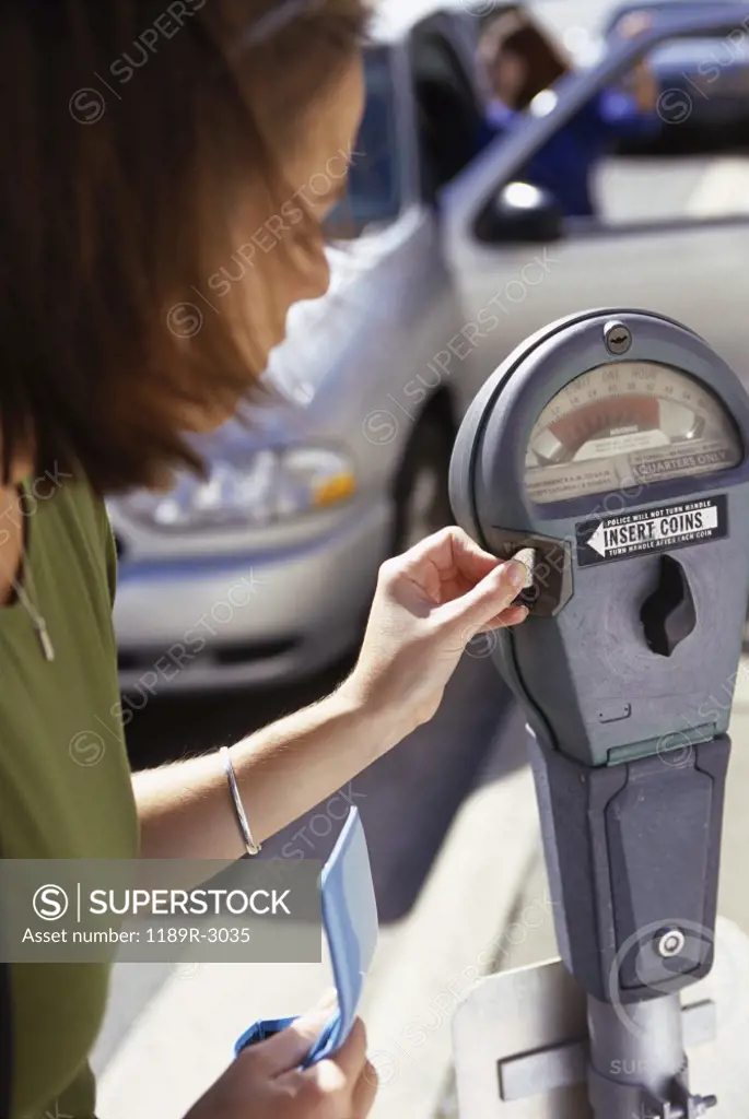 Side profile of a young woman feeding an expired parking meter
