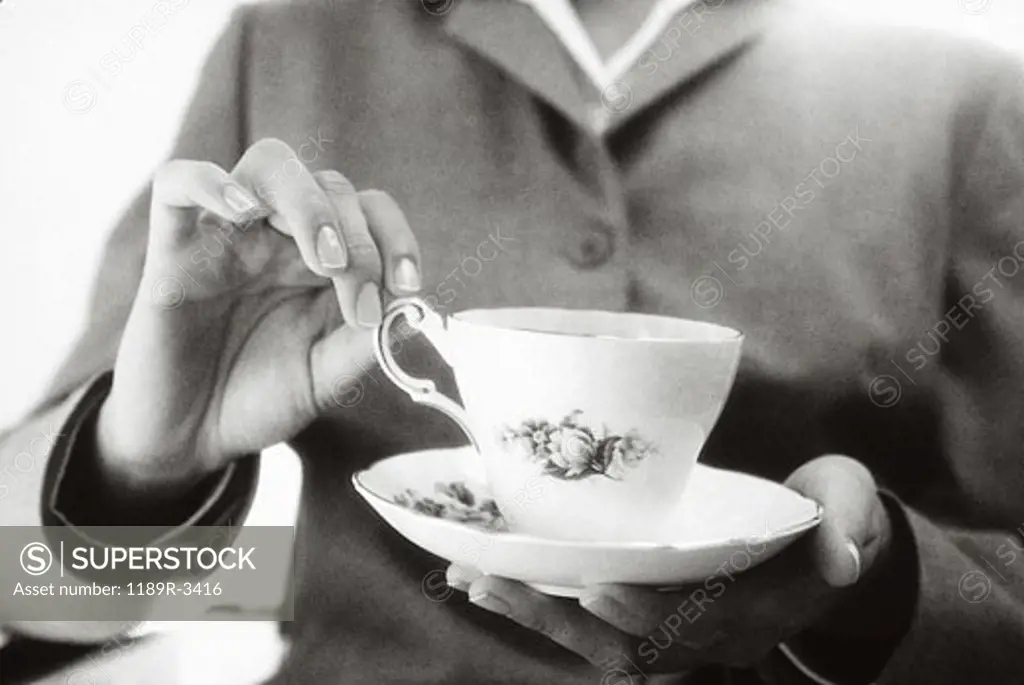 Close-up of a woman's hand lifting a teacup from a saucer