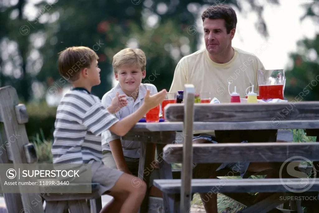 Father with his two sons seated on a picnic table
