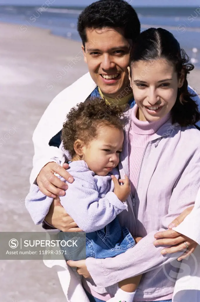 Portrait of a father and mother on the beach with their daughter