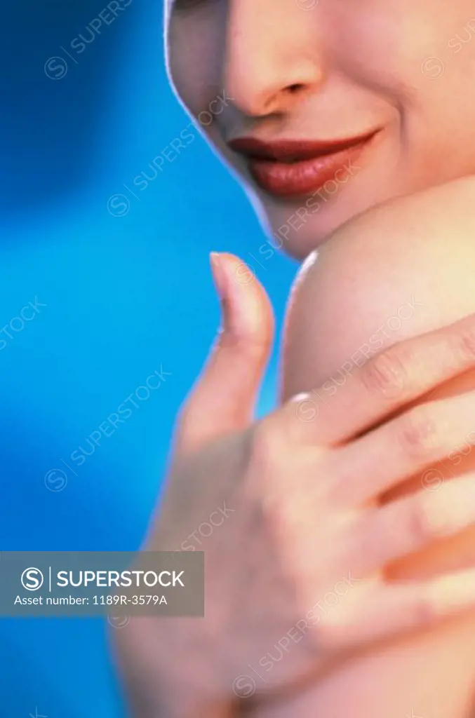 Close-up of a young woman applying moisturizer on her shoulder