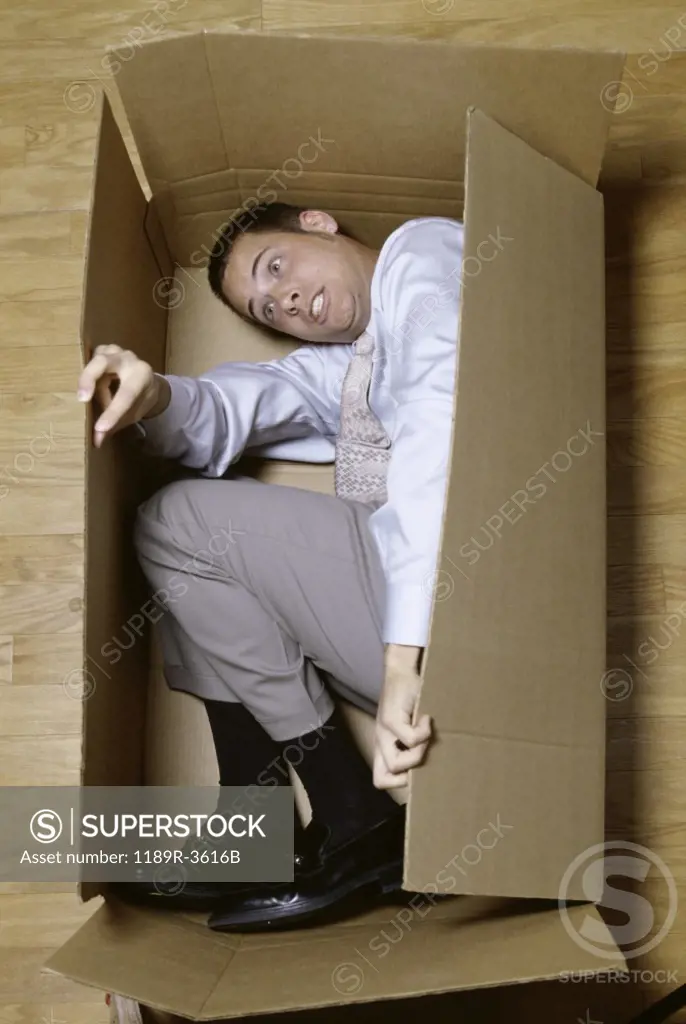 Businessman lying in a cardboard box