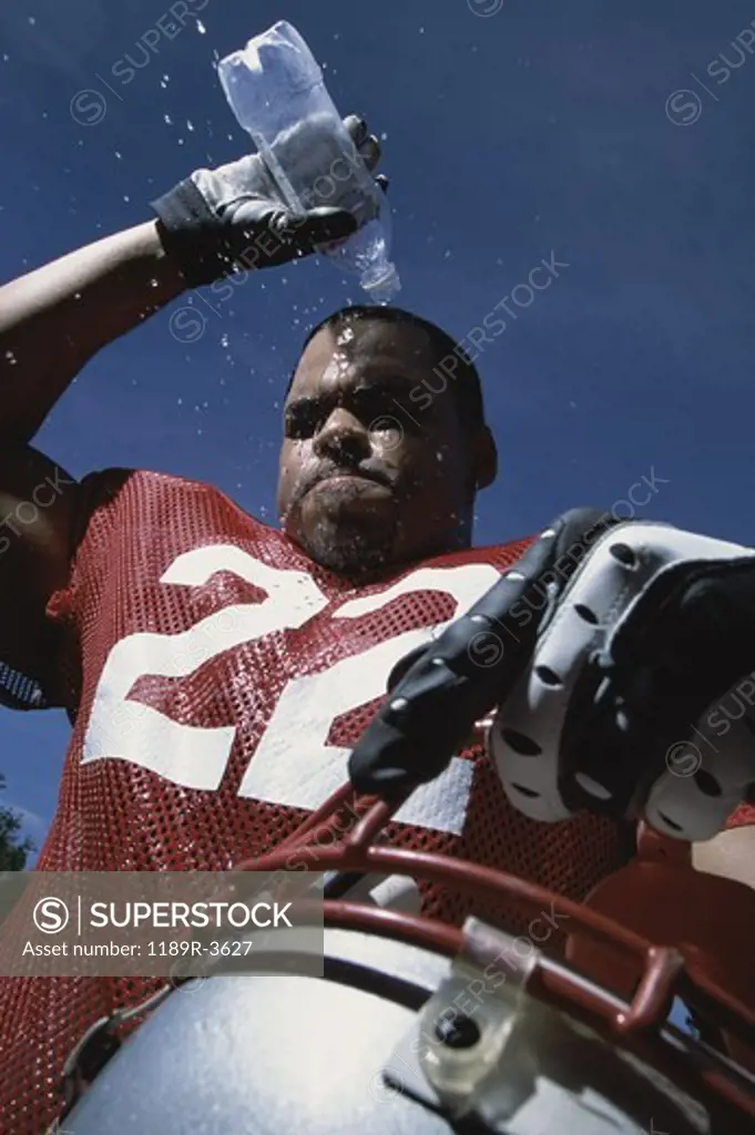 Low angle view of an American football player pouring water on his head