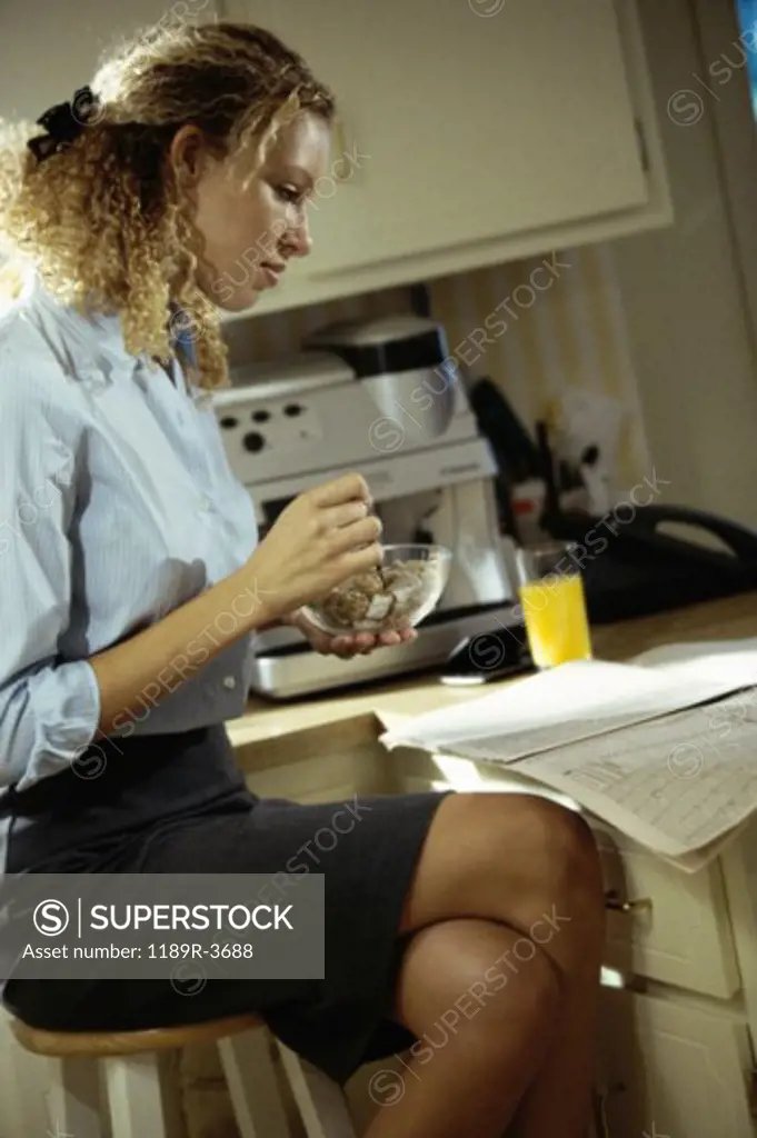 Side profile of a young woman sitting at a kitchen counter