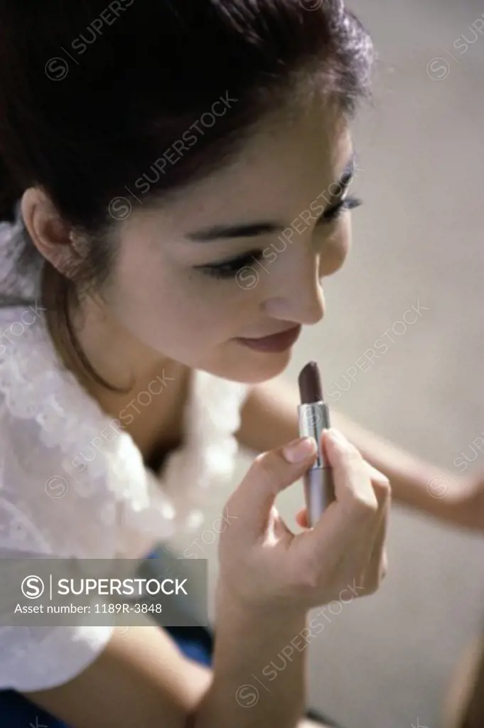 High angle view of a young woman applying lipstick