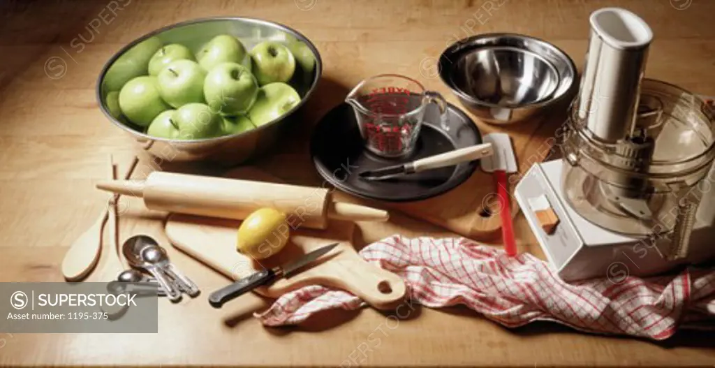 High angle view of granny smith apples and a juicer with kitchen utensils