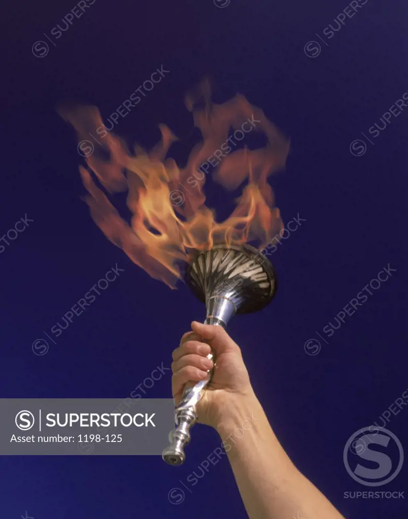 Person's hand holding a flaming torch