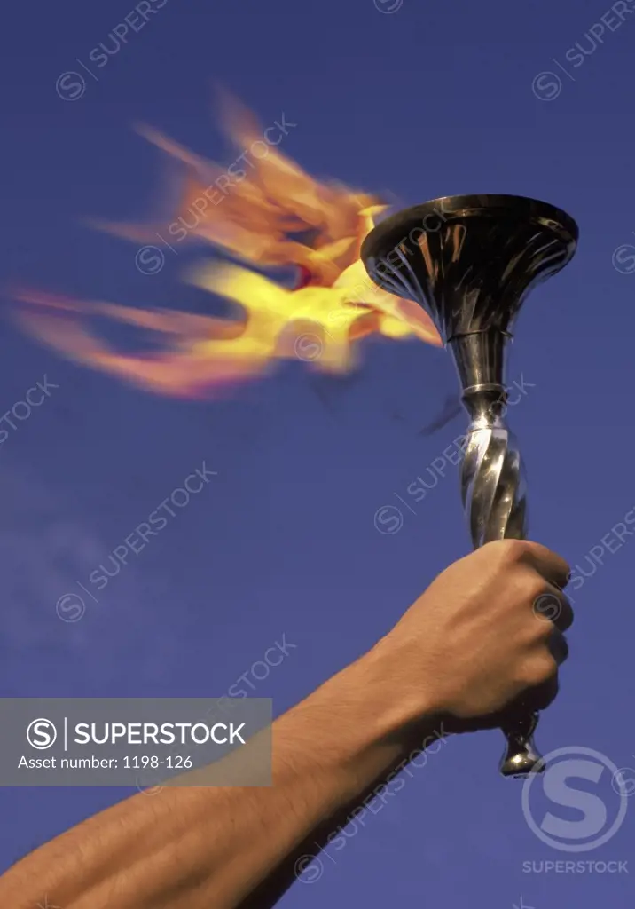 Person's hand holding a flaming torch