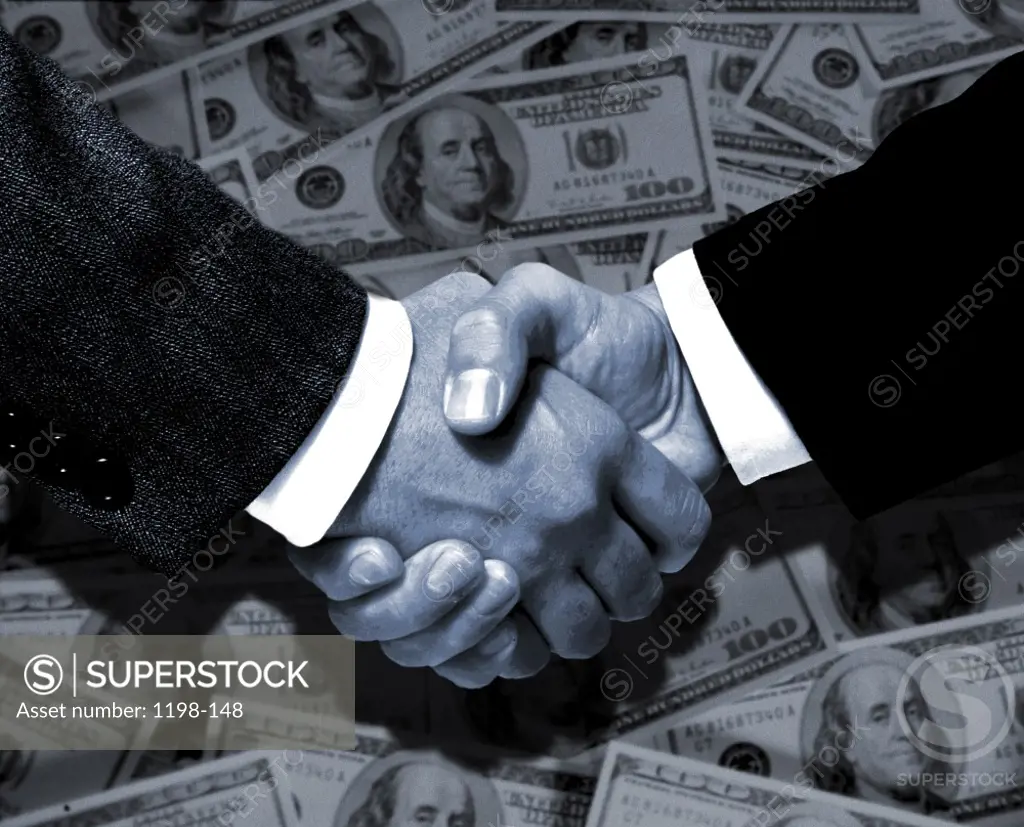 Businessman shaking hands in front of American dollar bills