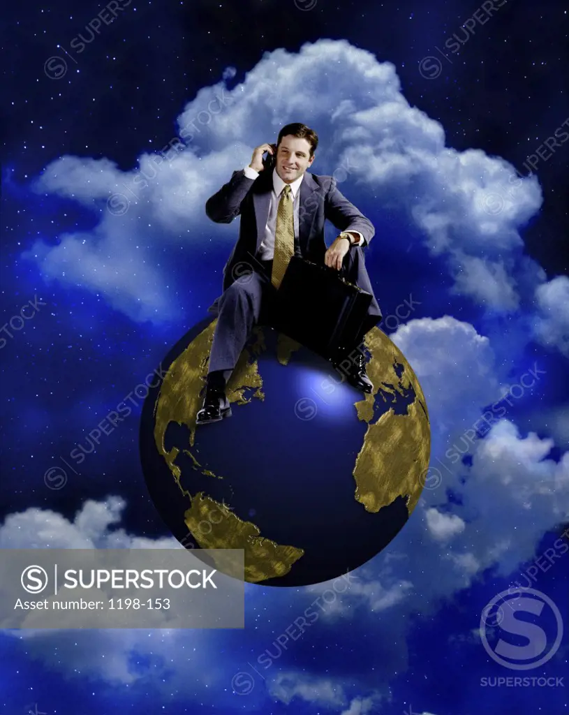 Businessman sitting on a globe talking on a mobile phone