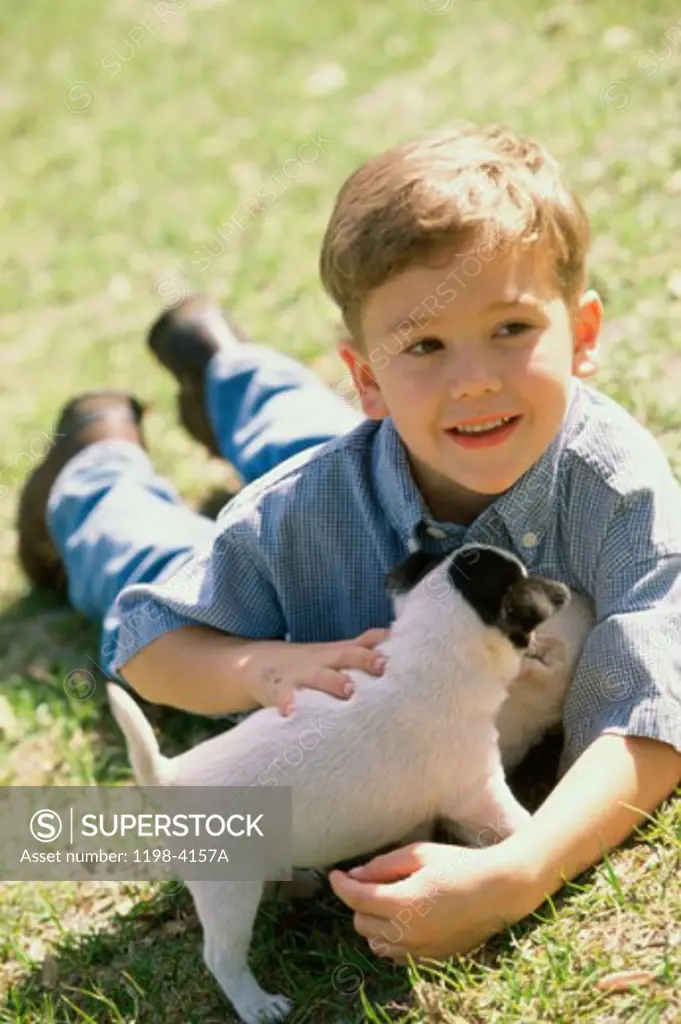 Close-up of a boy lying down in a park with a puppy