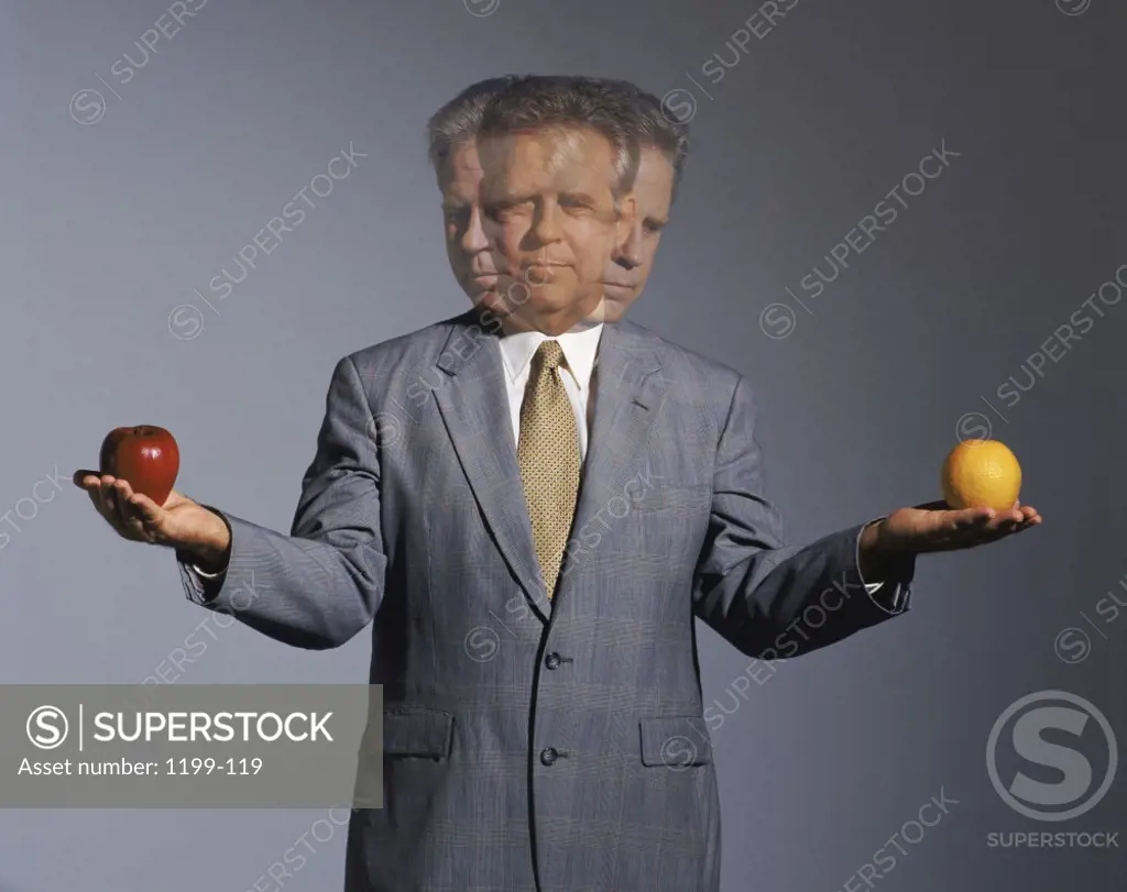Businessman holding an apple and an orange