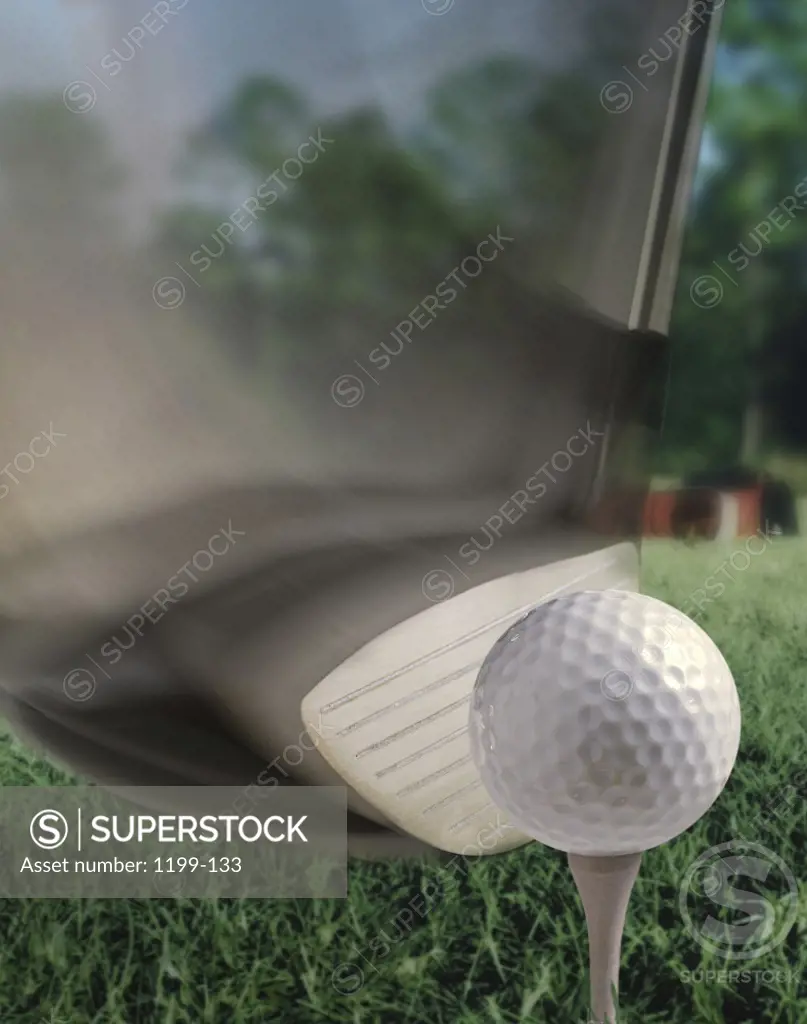 Close-up of a golf club hitting a golf ball on a tee