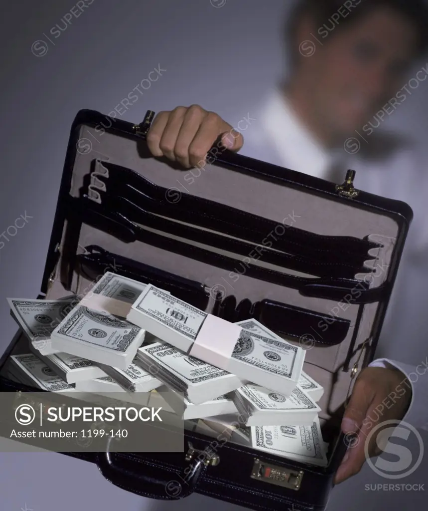 Businessman holding an open briefcase with American dollar bills