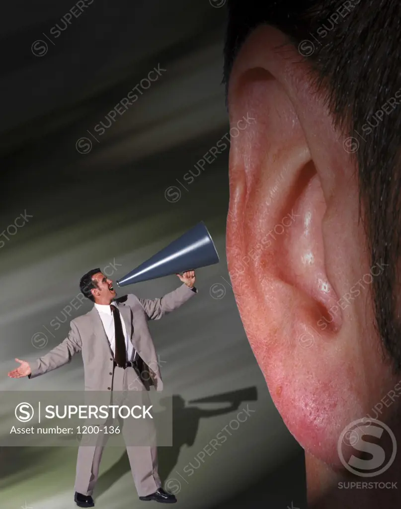 Businessman shouting into a megaphone in front of a person's ear