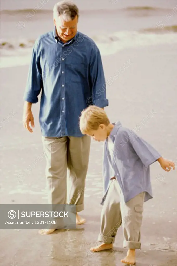 Senior man walking with his grandson on the beach