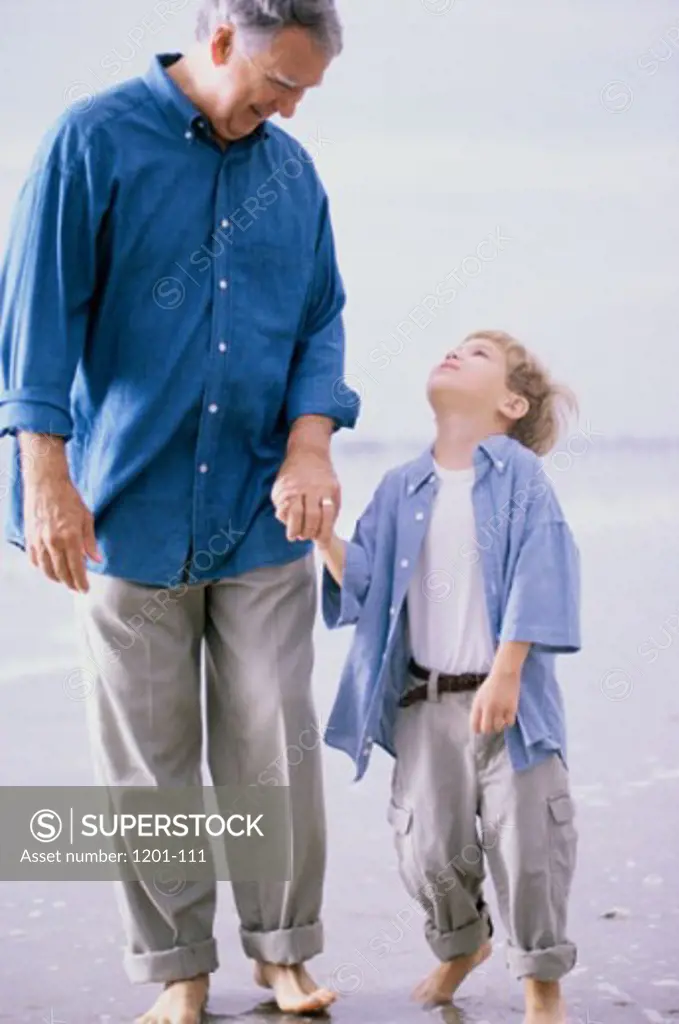 Grandfather and his grandson walking on the beach