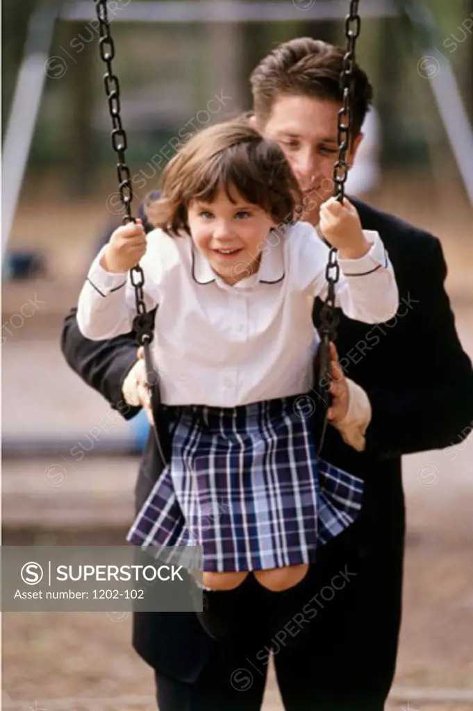Father pushing his daughter on a swing