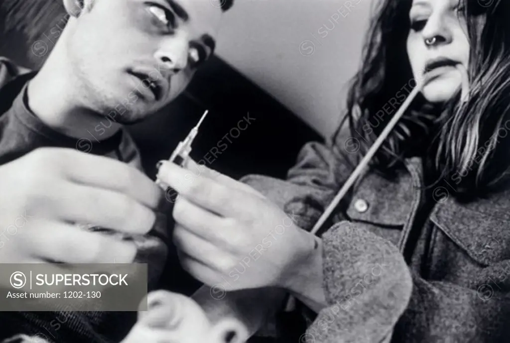 Close-up of a young man giving a narcotic injection to a young woman