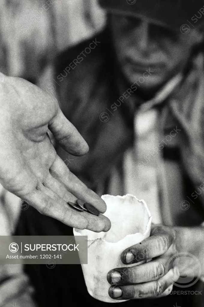 Person's hand putting money into a senior man's cup