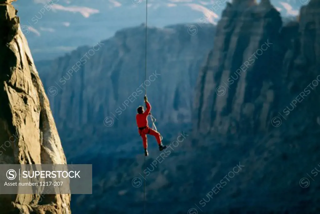 Rear view of a man rappelling down a rock