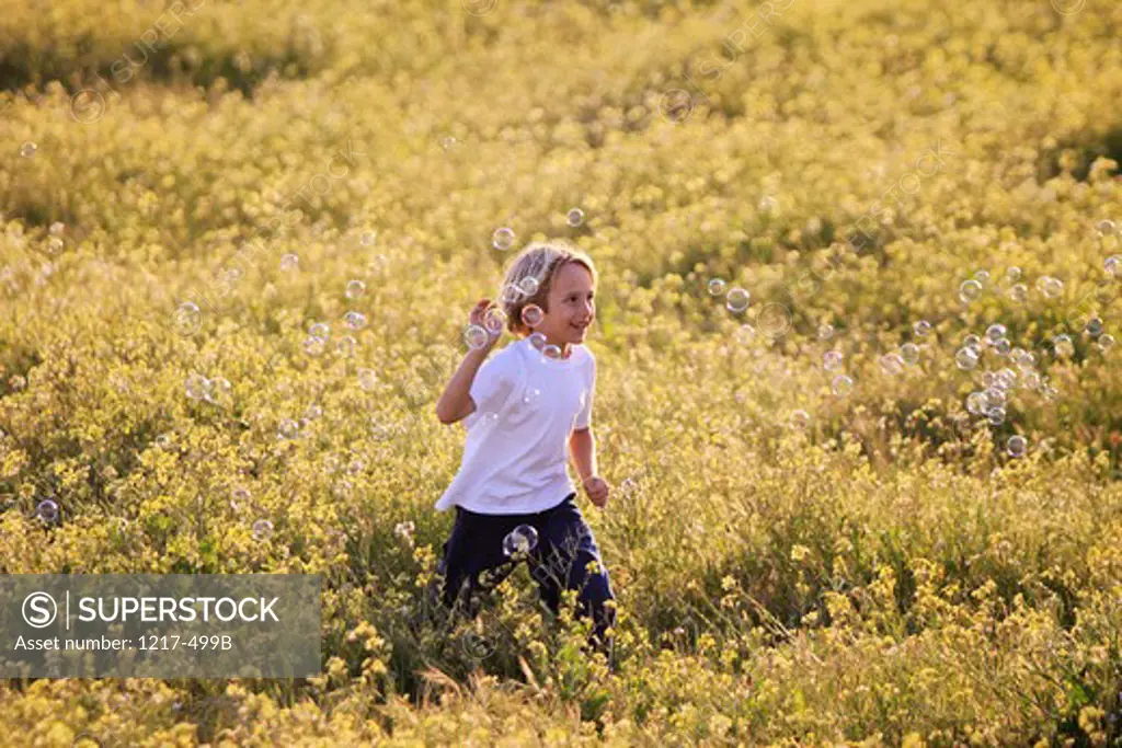 Boy playing with bubbles in a field