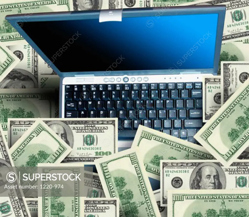 High angle view of a laptop with a group of one hundred dollar bills around it
